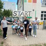 dzieci stoją pod napisem start trzymanym przez dwie kobiety.jpg