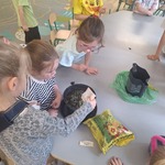 dzieci siedzą przy stoliku dziewczynka wsypuje ziarenka do doniczki.jpg