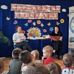 dwie kobiety siedzą przy stoliku i czytają dzieciom ksiązki.jpg
