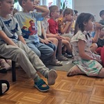 dzieci siedzą na ławkach i na podłodze.jpg