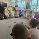 dzieci siedzą na dywanie i słuchają mężczyzny w czarnej koszulce.jpg