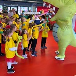 dzieci dają kolorowe balony panu przebranemu w strój dinozaura.jpg