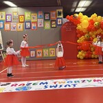dziewczynki w biało czerwonych strojach trzymają czerwoną wstążkę.jpg