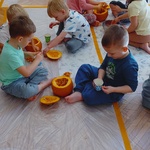 dzieci siedzą na podłodze na której stoją dynie.jpg