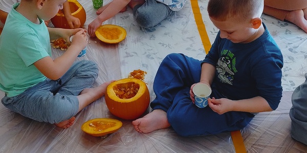 dzieci siedzą na podłodze na której stoją dynie.jpg